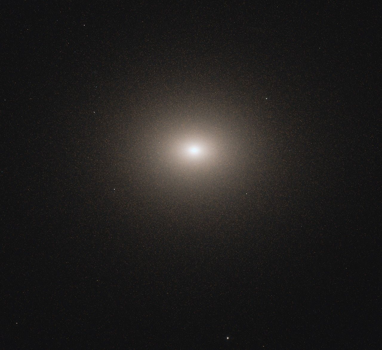 An oval-shaped, dwarf galaxy is centered in the image. Its bright-white core and more diffuse edges sit against a black background.